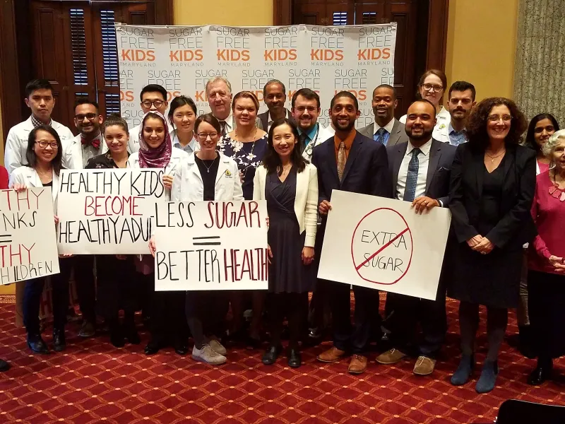 A diverse group holding signs supporting sugar free kids