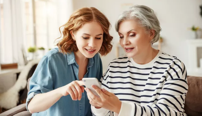 a mother and daughter reading an iPhone