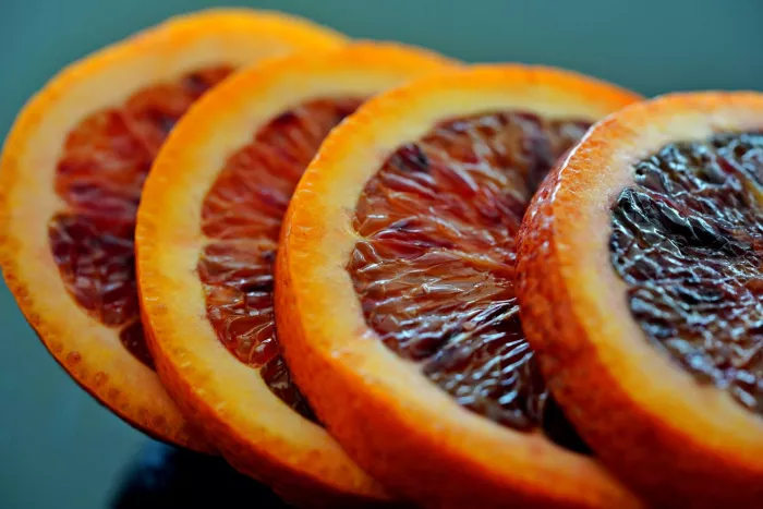 April produce - Sliced blood oranges on a green background