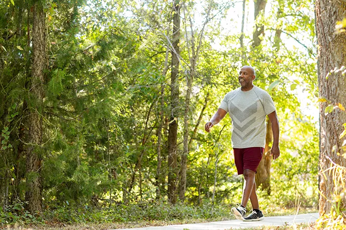 man walking on a trail in the sunny woods