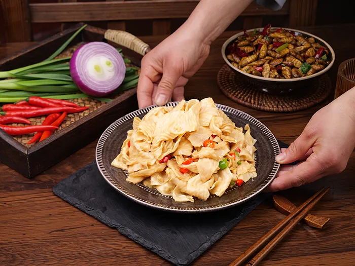 person placing plate of yuba down next to vegetable