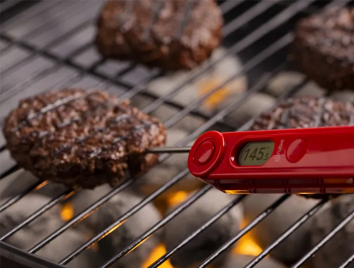 electric thermometer in burger patty on a grill