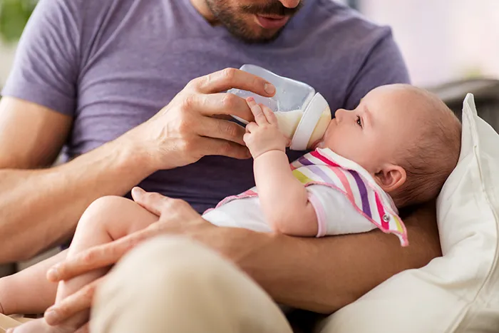 man holding baby and feeding them a bottle