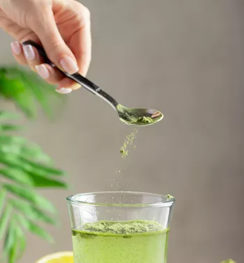 green powder being pored into glass of water