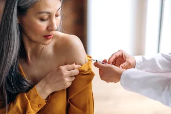 middle aged woman getting a vaccine in her arm