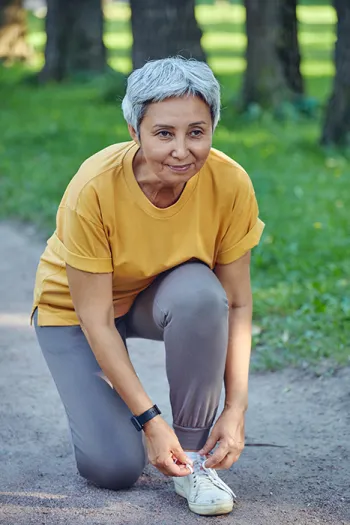 woman tying her shoe on sidewalk