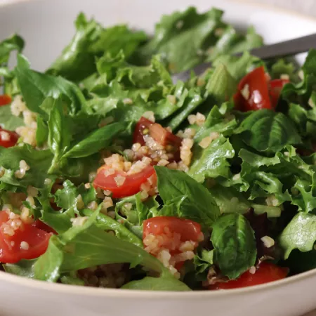 sliced tomato and cooked bulgur over leaf lettuce