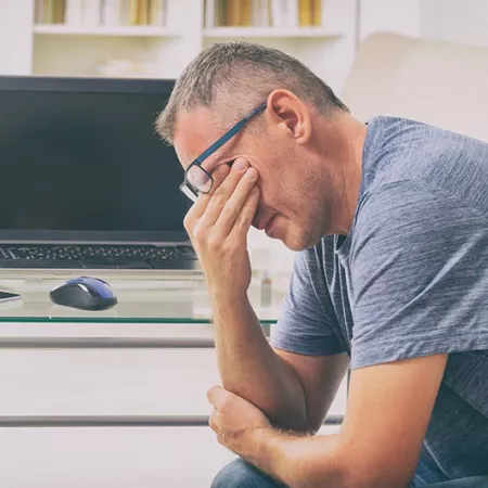 man sitting down and rubbing eyes