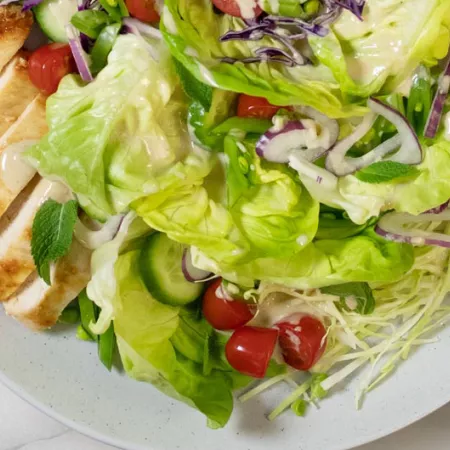 salad with greens, chicken, cucumber, and tomato