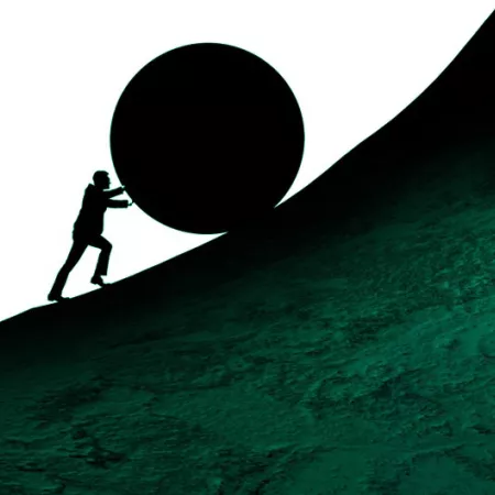 man pushing a rock up a hill