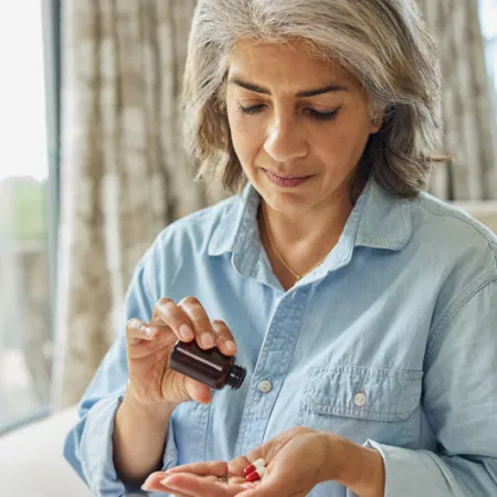 Woman pouring supplements into her hand from bottle