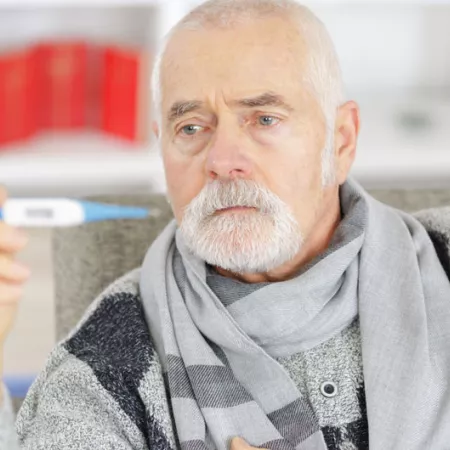older man in scarf looking at thermometer