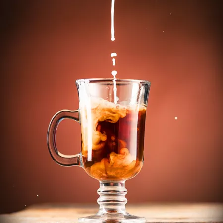 mug of coffee with creamer being poured in