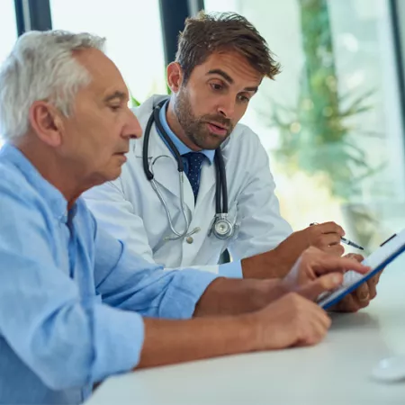 older man and doctor looking and pointing at a tablet