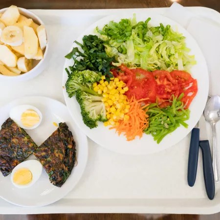 Vegetable salad, spinach omelette and fruit on tray