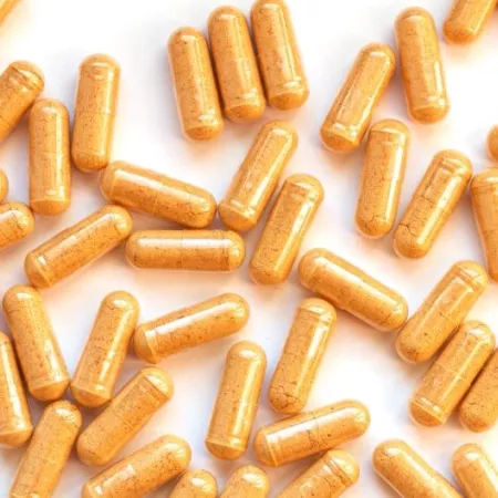 Capsules of yellow powder scattered on a white background