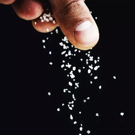 fingers sprinkling salt on a black background