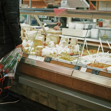 A man with flowers standing in front of a deli display containing various salads