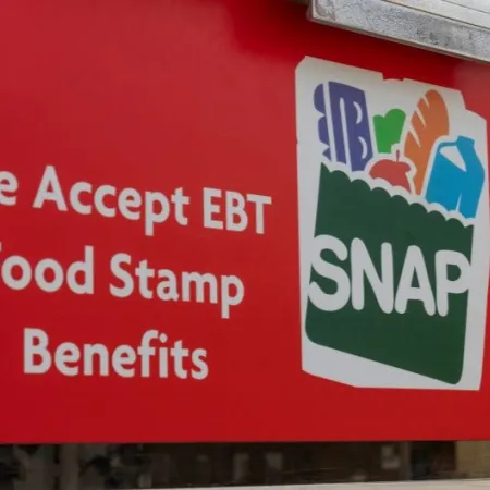A store window displays a red sign that reads "We accept EBT Food Stamp benefits" with the SNAP grocery logo.