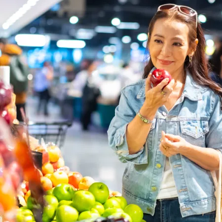 woman at grocery store holding a apple in the produce section