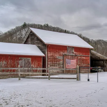 A shabby red barn with an American flag hanging on the side