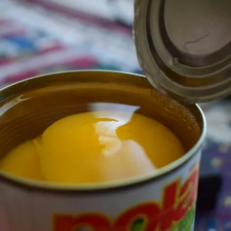 An open can of peaches in heavy syrup. 