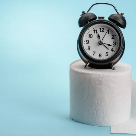 alarm clock sitting on a roll of toilet papper