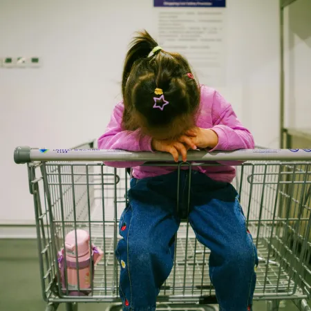 A little girl sitting in an empty shopping cart.