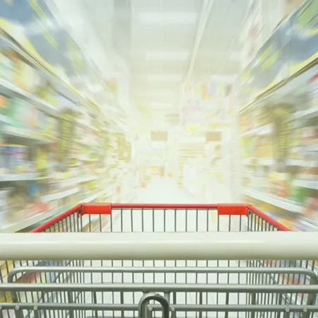 grocery cart in focus in the foreground with grocery store shelves out of focus in the background